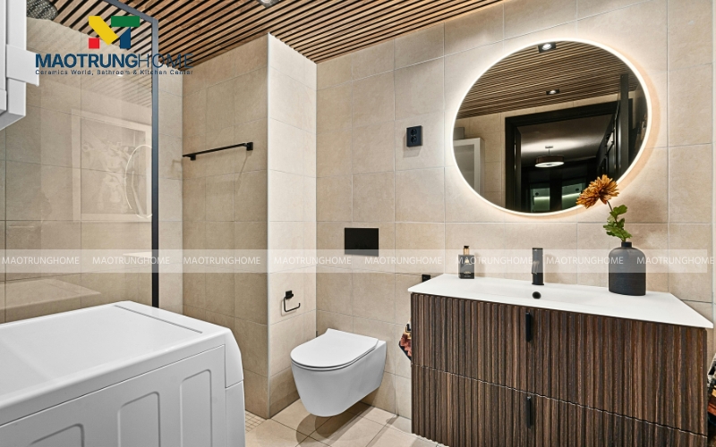 Nhà vệ sinh nhỏ với một chiếc tủ lavabo mặt gỗ màu tối và gương tròn