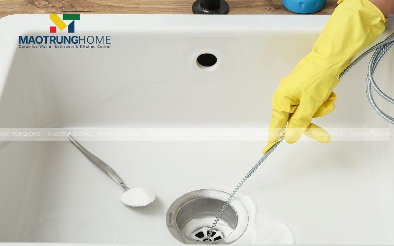 Luồn đầu dây lò xo vào đường ống thoát nước của bồn tắm